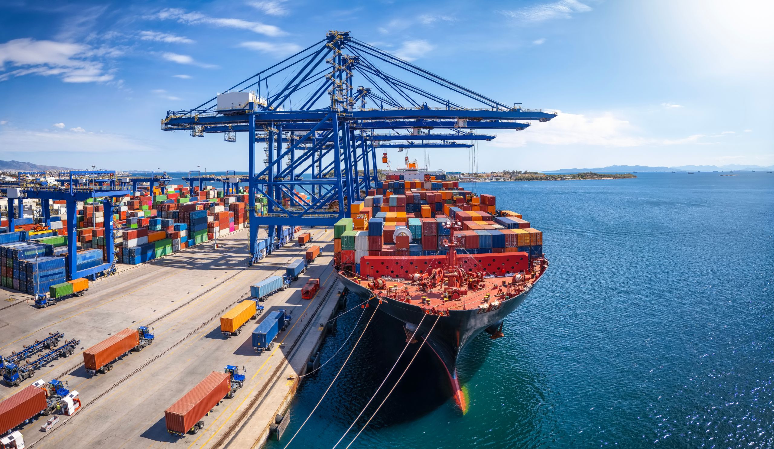 A large container cargo ship is beeing loaded and unloaded in a commercial dock Large container ship docked at a busy seaport with cranes and colorful shipping containers.